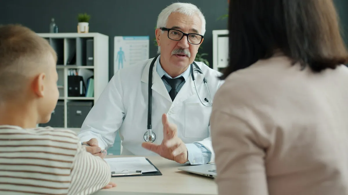 A doctor talking with a mother and her young son across a desk