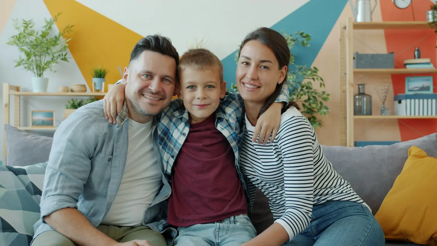Mother, father and son smiling together on their living room sofa